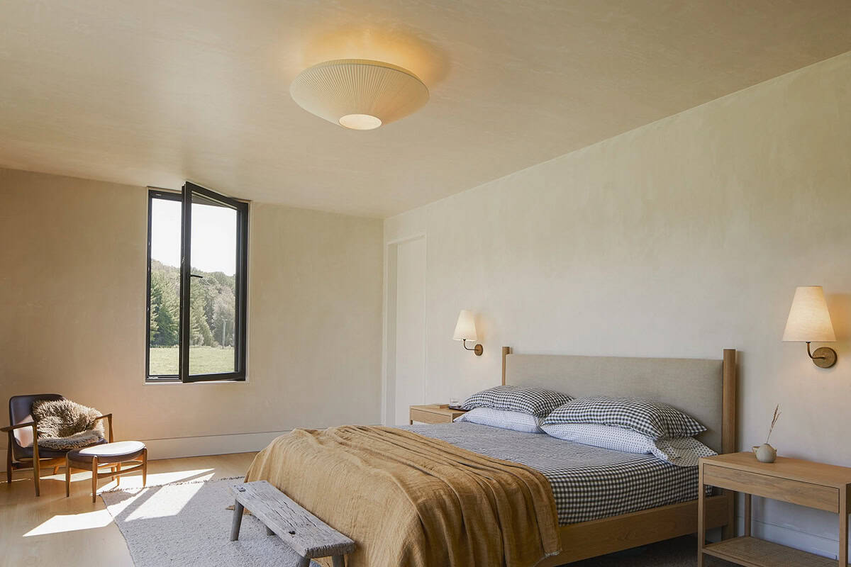 Primary bedroom with plaster walls, gingham bedding, and oak nightstands
