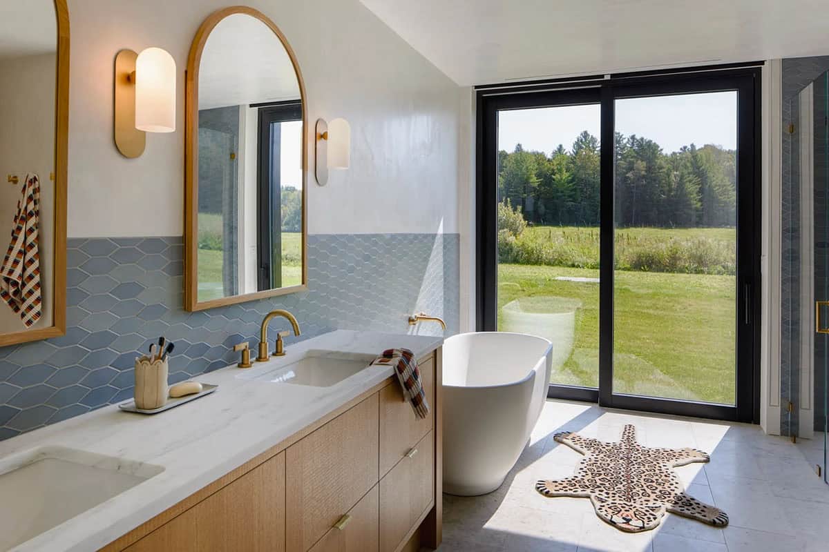 Bathroom with blue hexagon tile, arched mirrors, freestanding tub, and field view