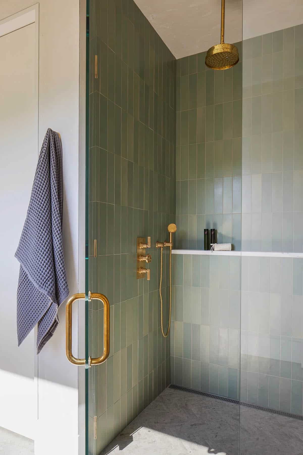 Shower with vertical green tile and unlacquered brass fixtures