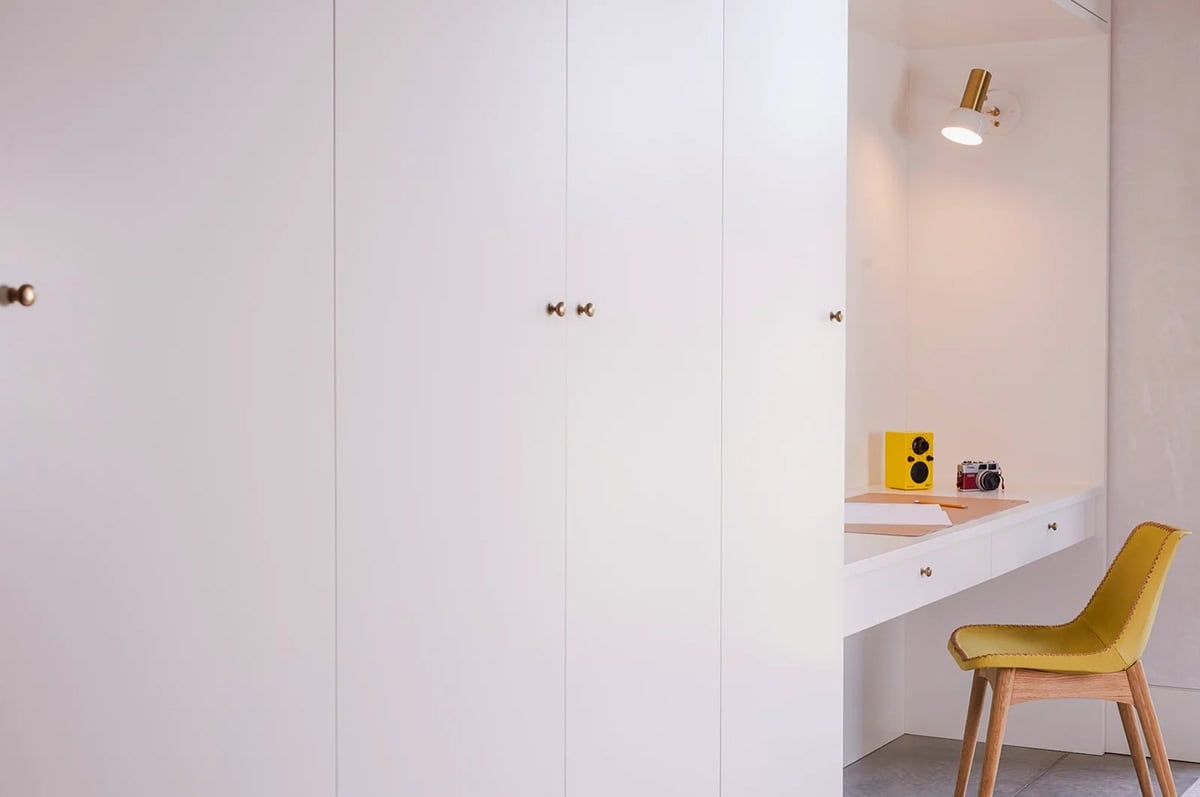 White built-in cabinets and desk nook with yellow chair