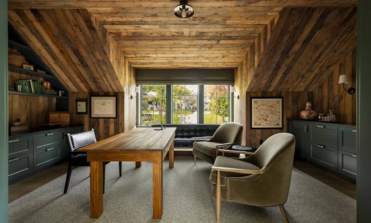 Barnwood-lined home office with a tufted black leather window seat under a trio of windows, a wood desk and green lower cabinets