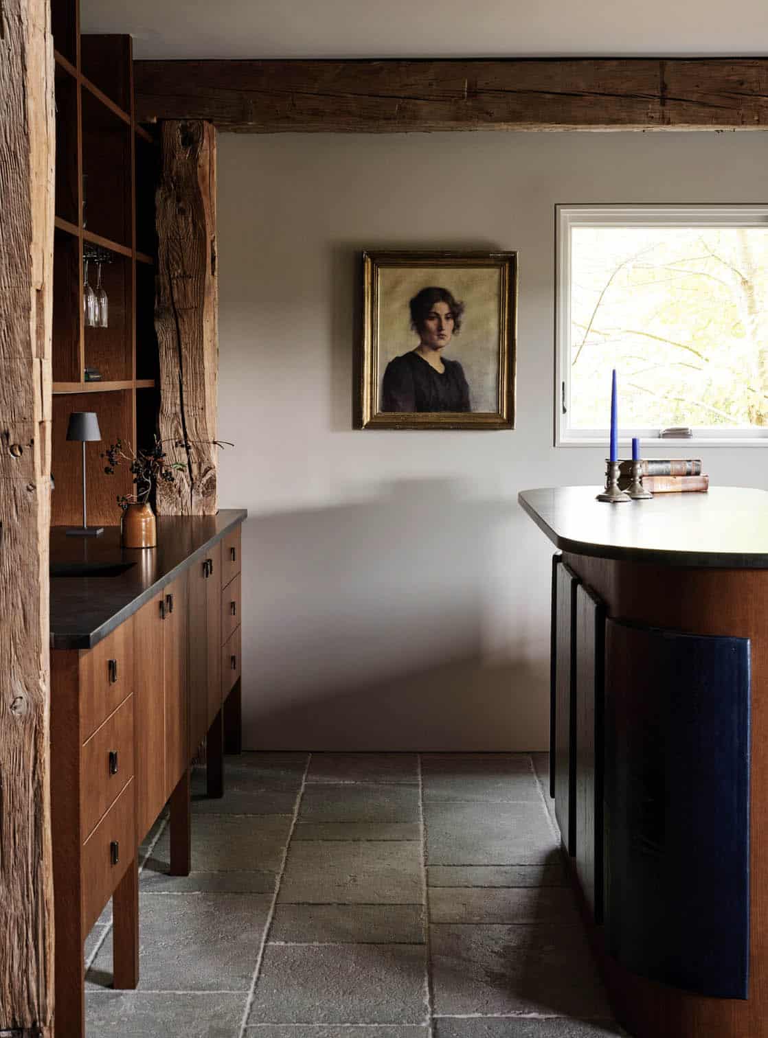 Bar area with oak cabinets, stone floor and an antique portrait of a woman in a gilt frame