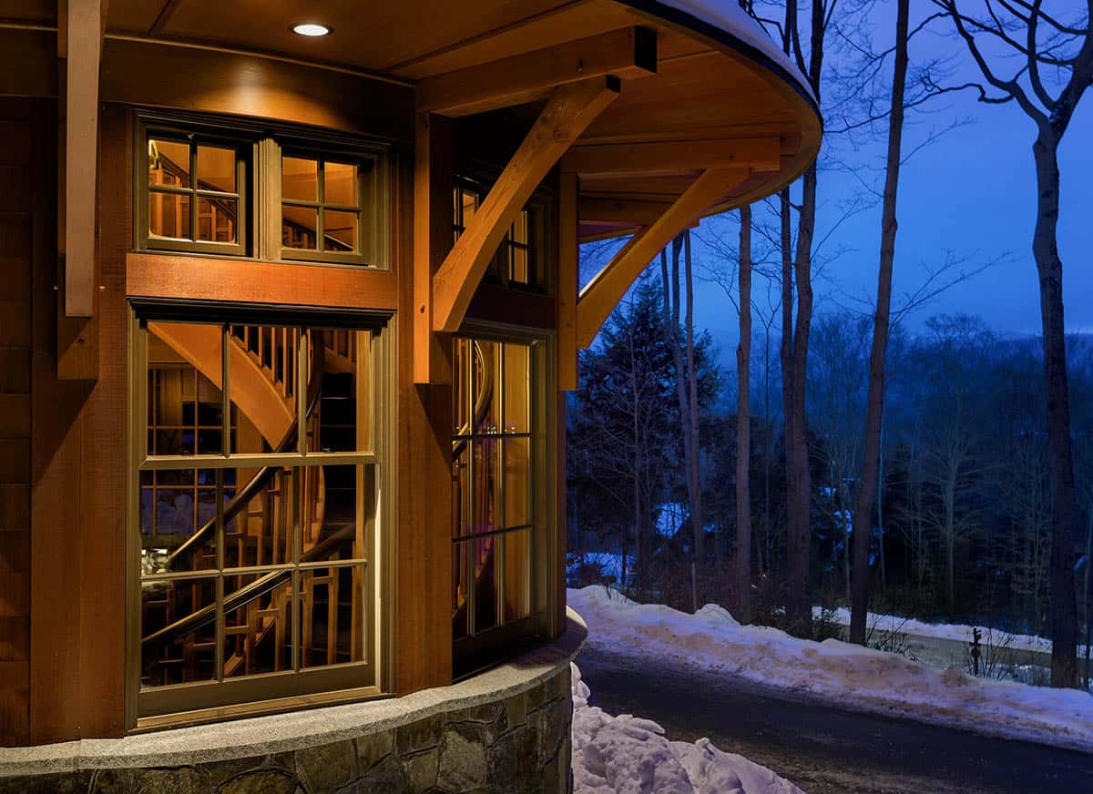 Curved timber brackets beneath a sweeping eave, with windows showing a spiral staircase inside the turret