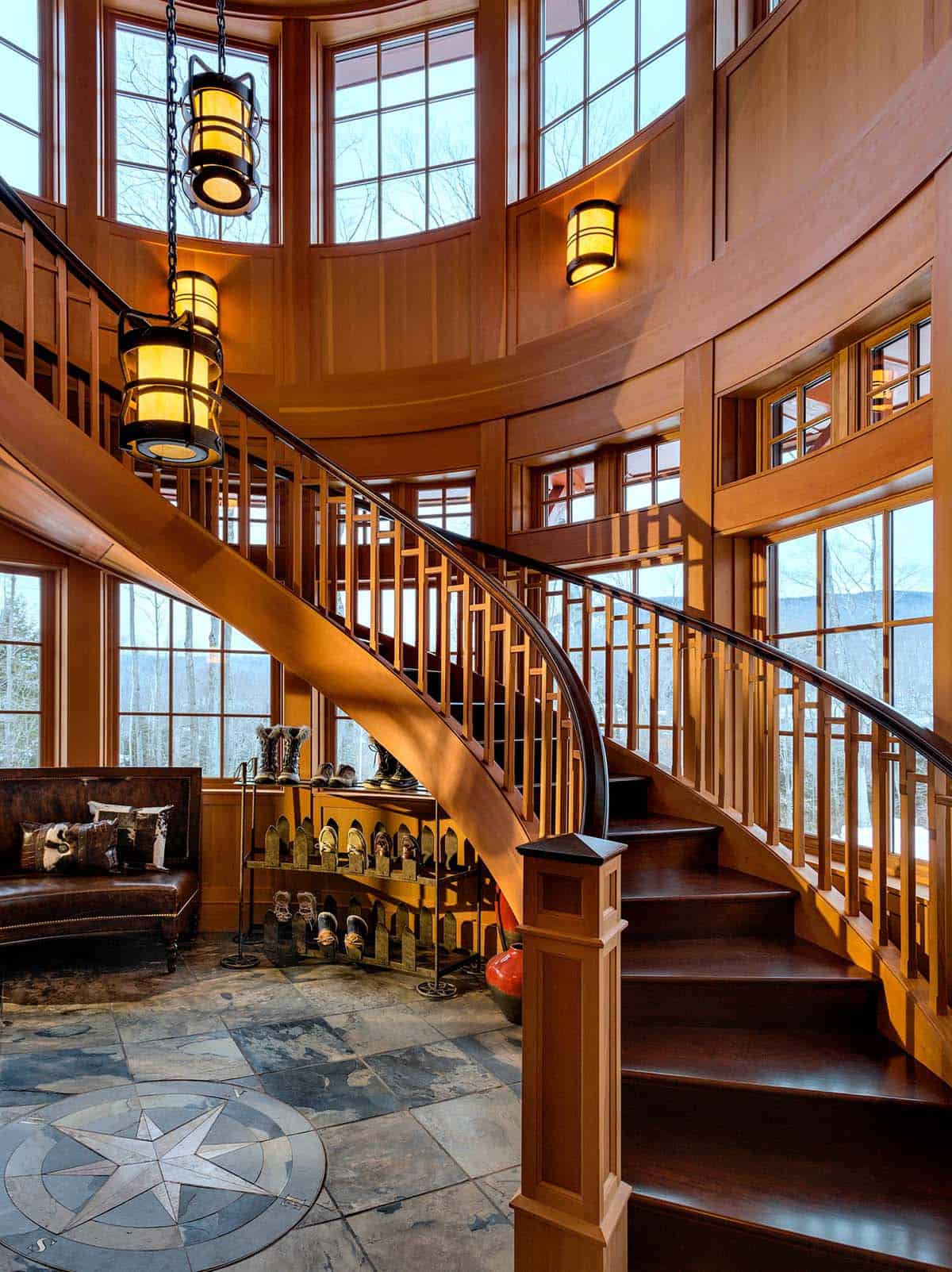 Lantern pendants hanging in a tall round stair tower lined with wood paneling and windows