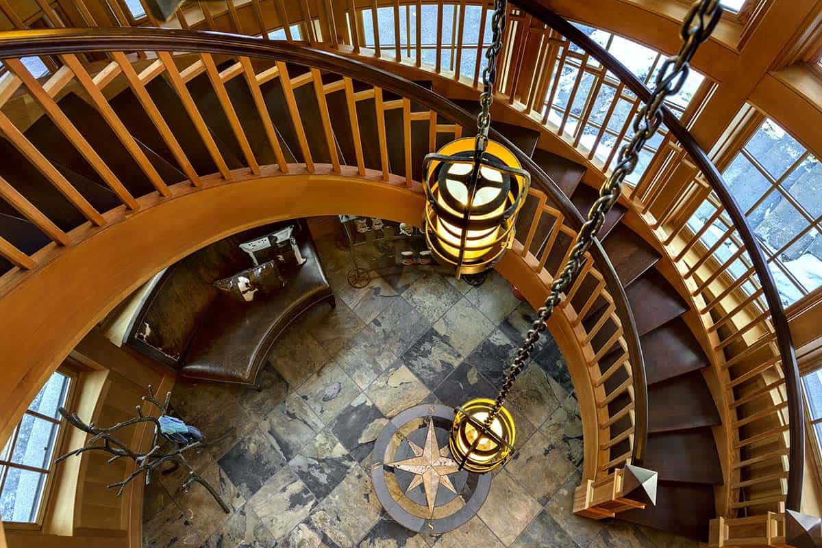 Looking down a spiral staircase onto a slate floor with a compass rose medallion