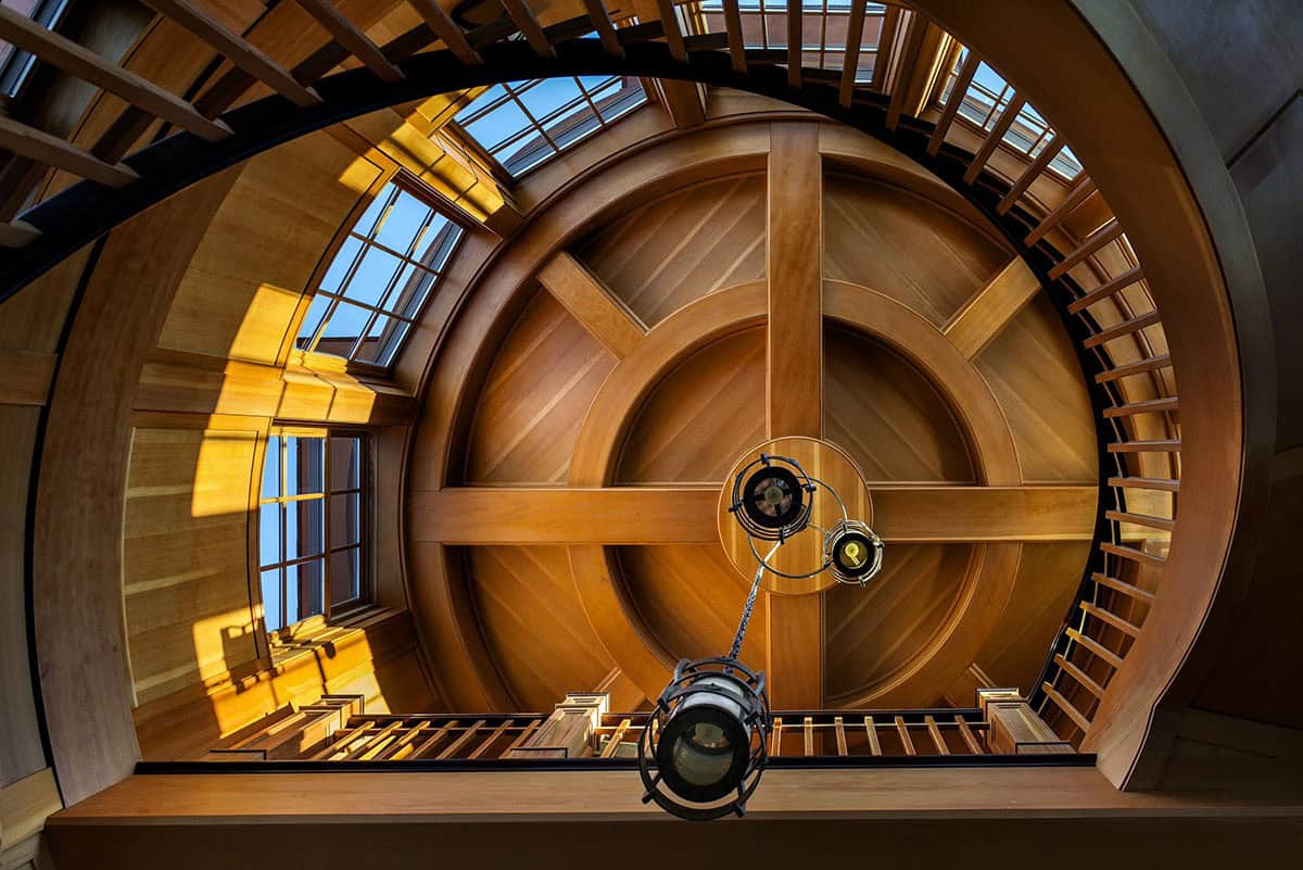 Looking up at a radial coffered wood ceiling with skylights at the top of the stair tower