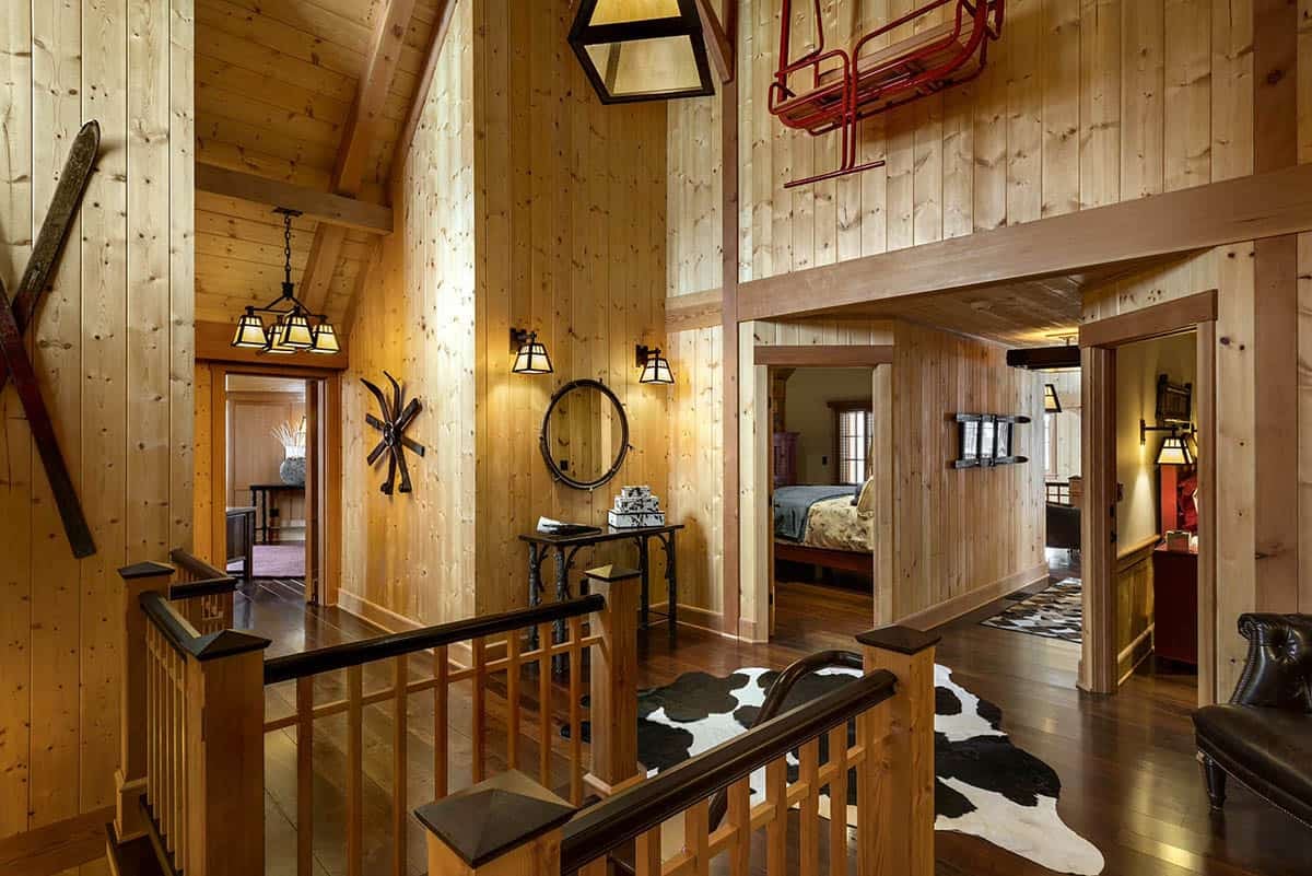 Upper hallway with a vintage red chairlift mounted high on the wall, crossed wooden skis and a cowhide rug