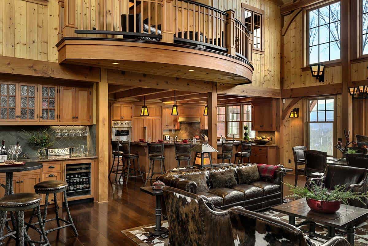Great room with leather sofas, a bar with twig-style stools and the kitchen beneath a curved balcony