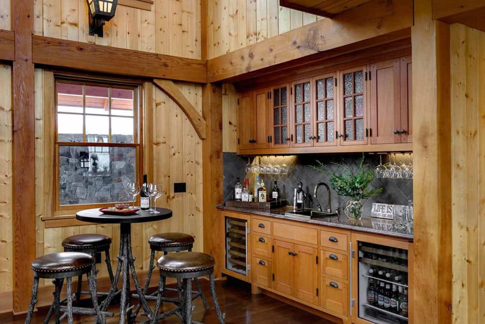 Bar area with glass-front cabinets, a wine refrigerator and a twig-base pub table with leather stools