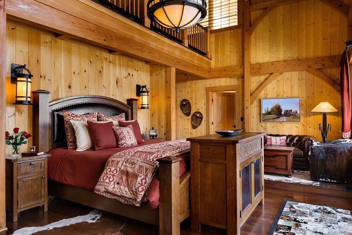 Bedroom with a leather-paneled bed, timber loft above, vintage snowshoes on the wall and a sitting area