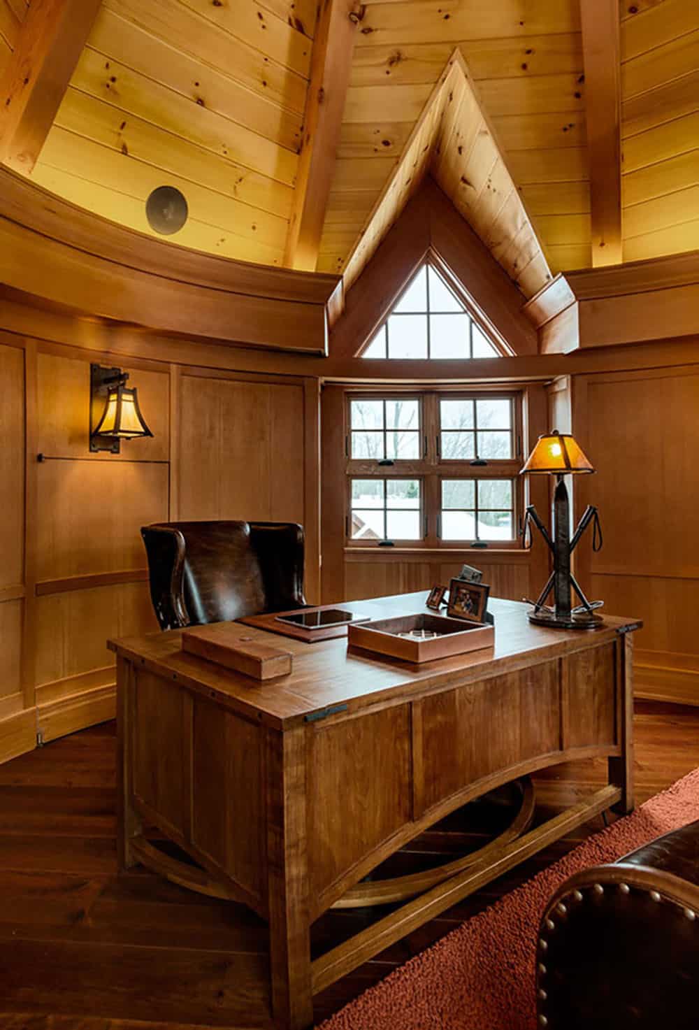 Turret home office with a pine ceiling, triangular gable window, wood desk and a lamp made from ski poles