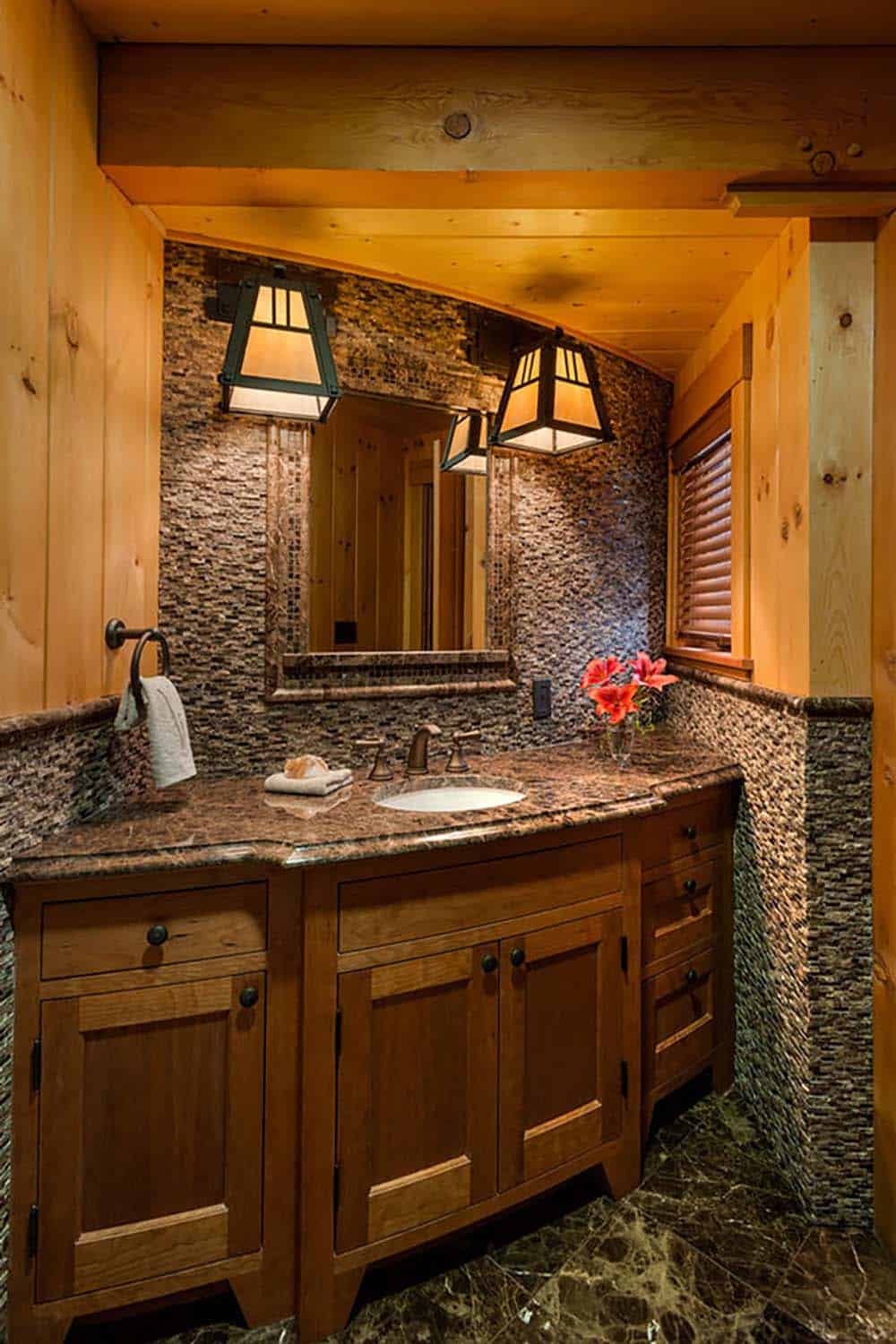 Powder room with cherry vanity, brown marble countertop, stacked stone mosaic walls and mica lantern sconces