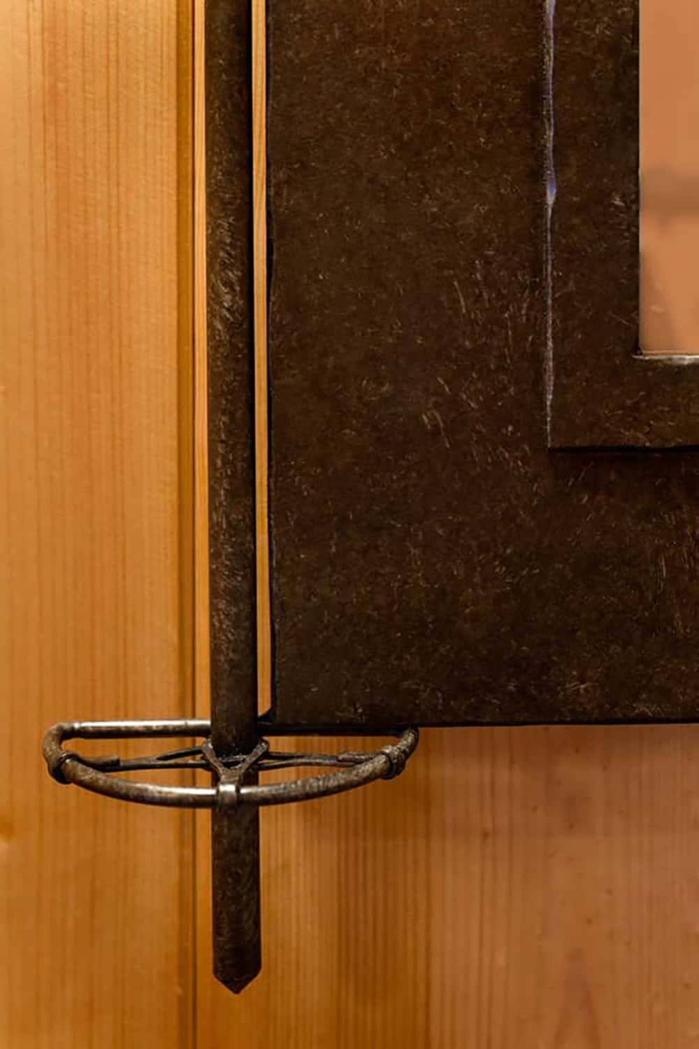 Close-up of a ski pole with a basket mounted along the edge of a dark metal mirror frame