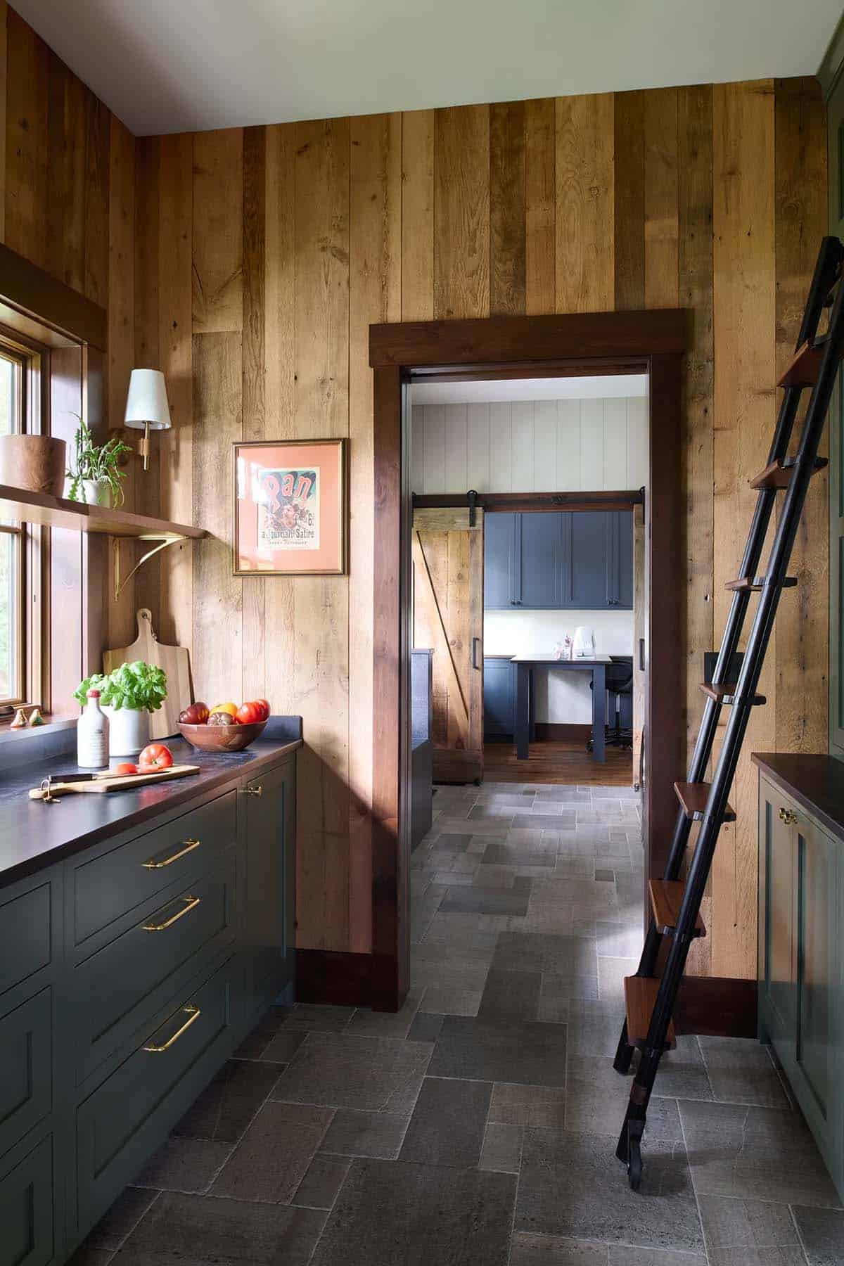 Pantry looking through a doorway to a room with blue cabinets, a work table and an open sliding barn door