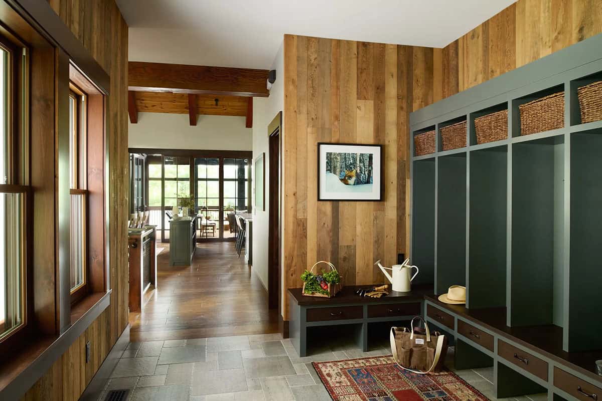 Mudroom with dark green lockers and woven baskets, reclaimed wood walls, a stone tile floor and a hallway leading to the kitchen
