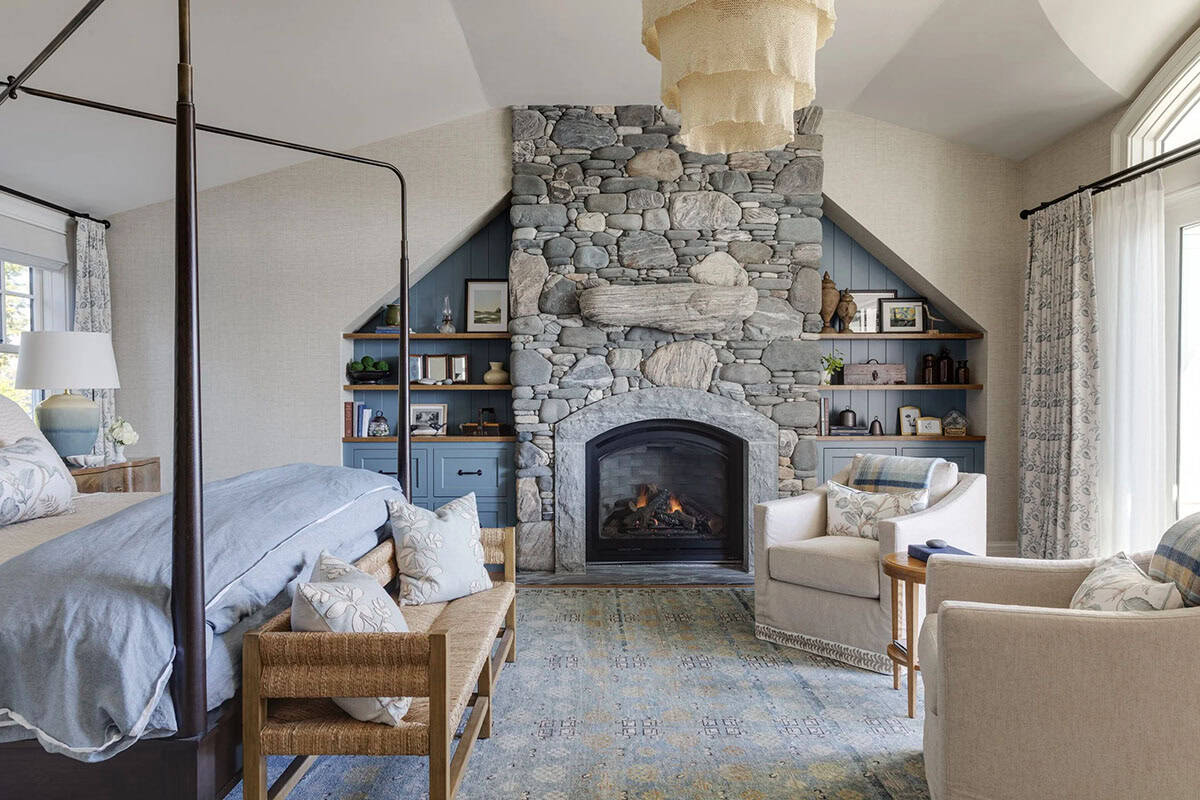 Primary bedroom with a four-poster bed, a stacked-stone fireplace flanked by blue built-in shelves, and a woven pendant