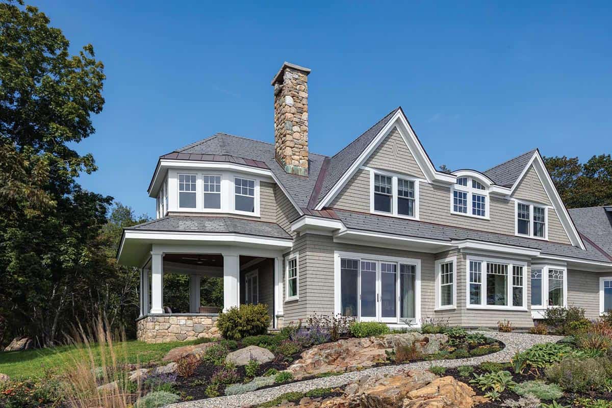 Corner of the house showing a stone-based covered porch, French doors, and a gravel path through rock gardens