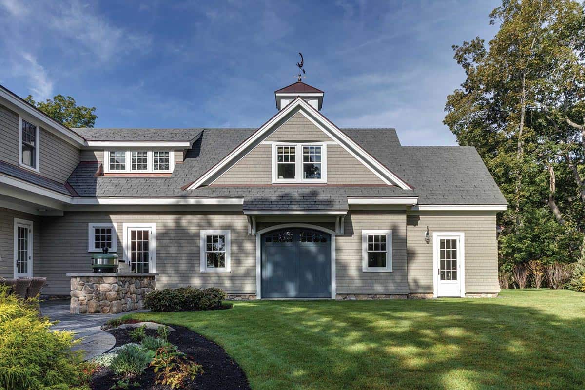 Garage wing with blue arched barn doors, cupola with weathervane, and a stone grill counter