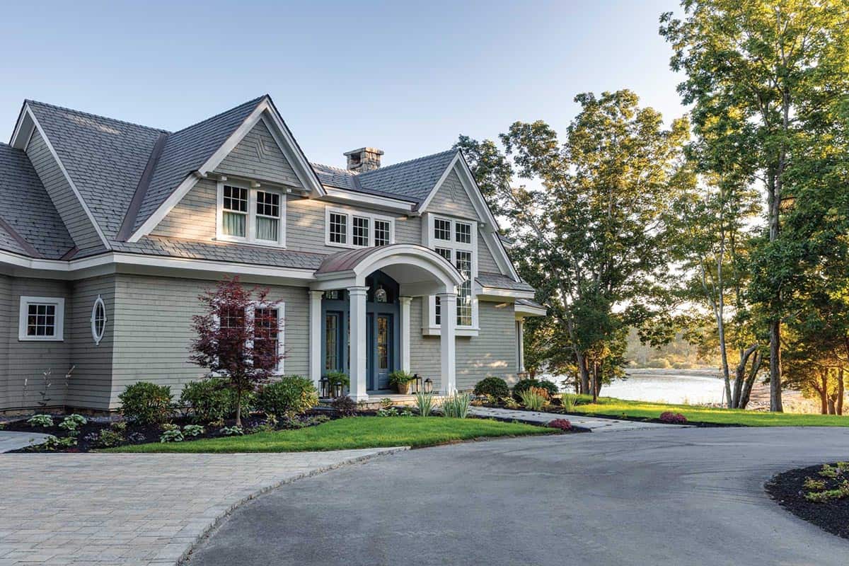 Front entry with a copper-roofed arched portico and blue double doors, with water visible through the trees