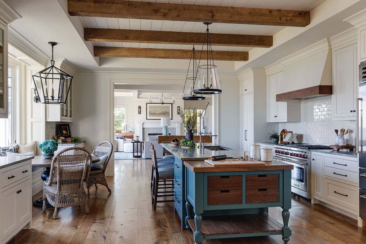 Kitchen with exposed wood beams, a teal island, white cabinetry, and lantern pendants