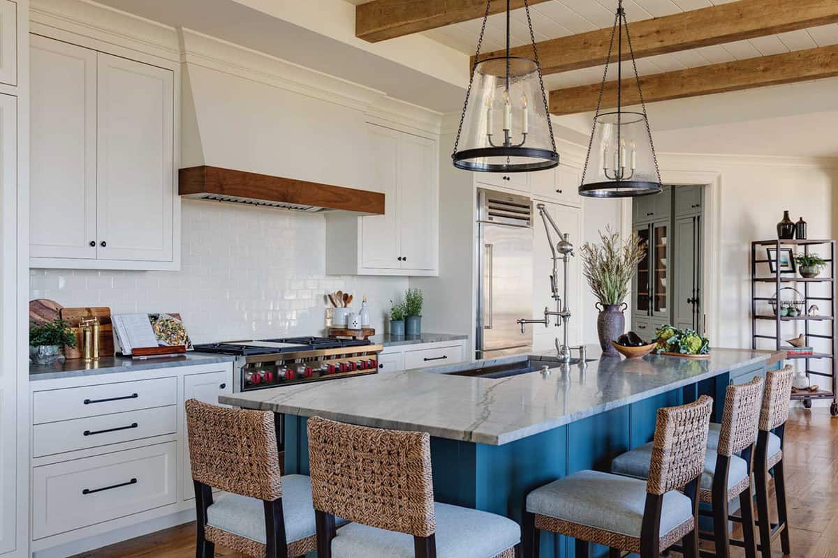 Kitchen island with a stone countertop, woven bar stools, and a walnut range hood above the stove