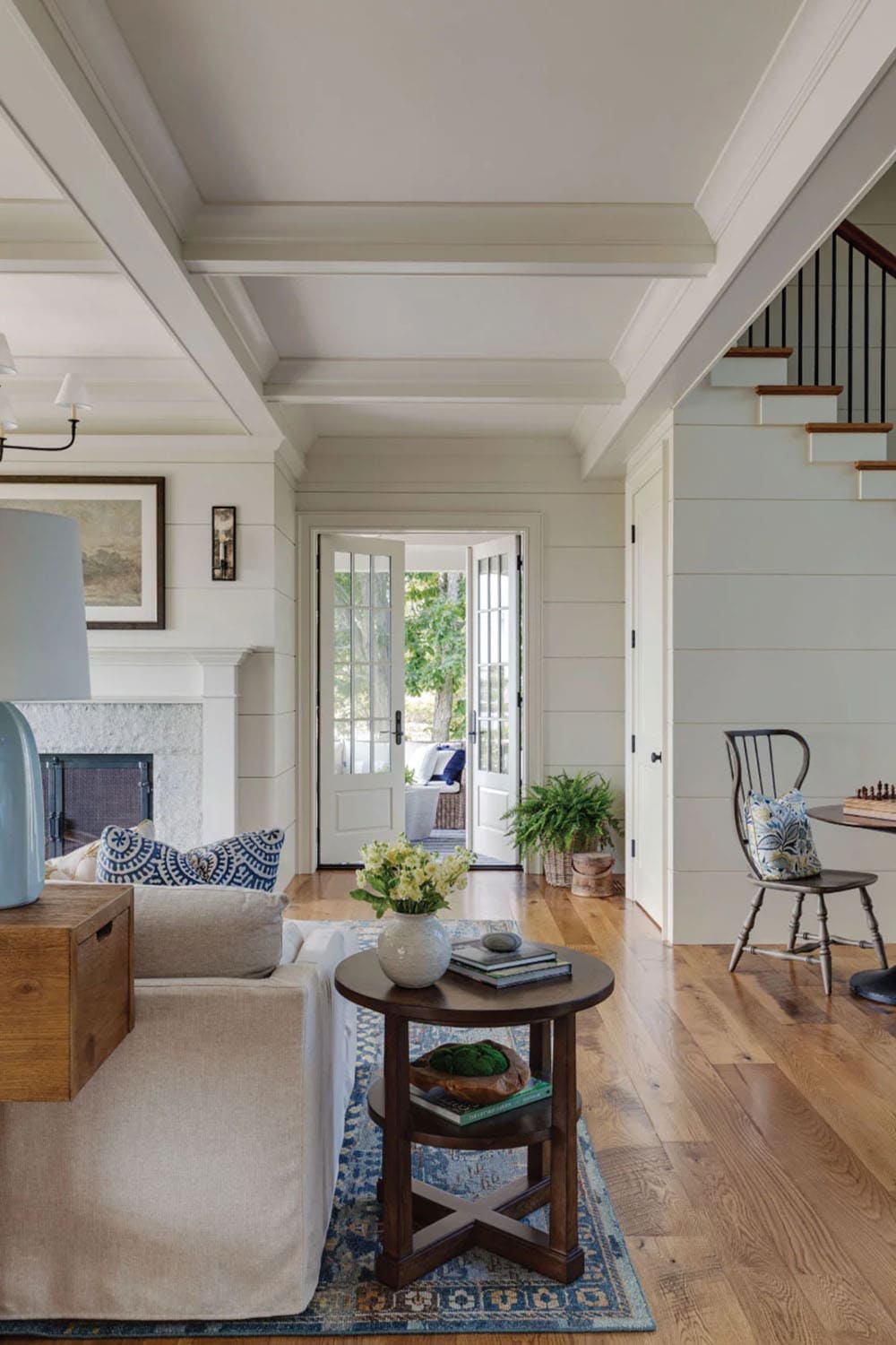 Hallway view of a coffered ceiling, shiplap walls, wide-plank oak floors, and open French doors to the porch