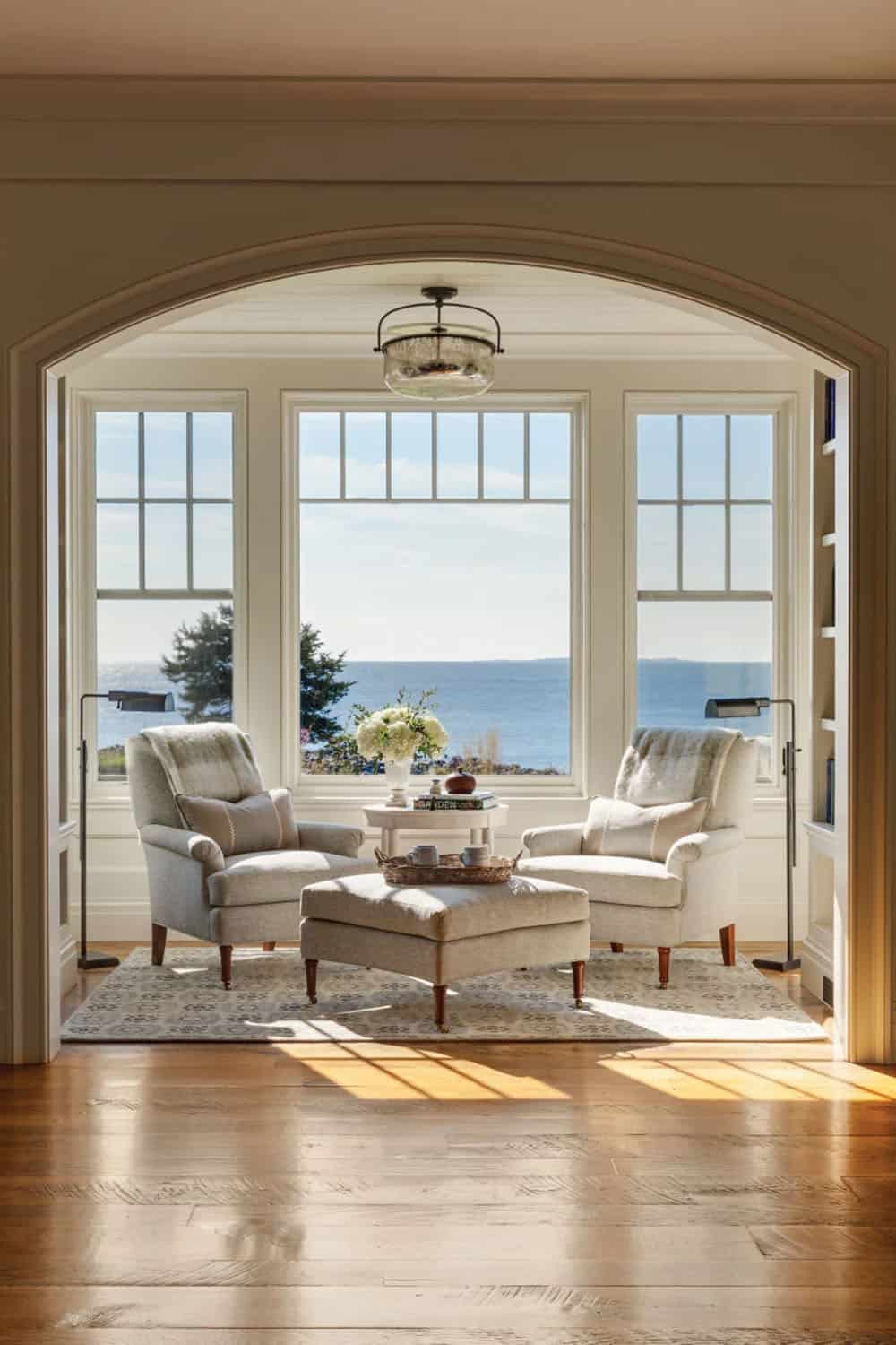 Sitting nook framed by an arched opening, with two armchairs facing a large window and the ocean