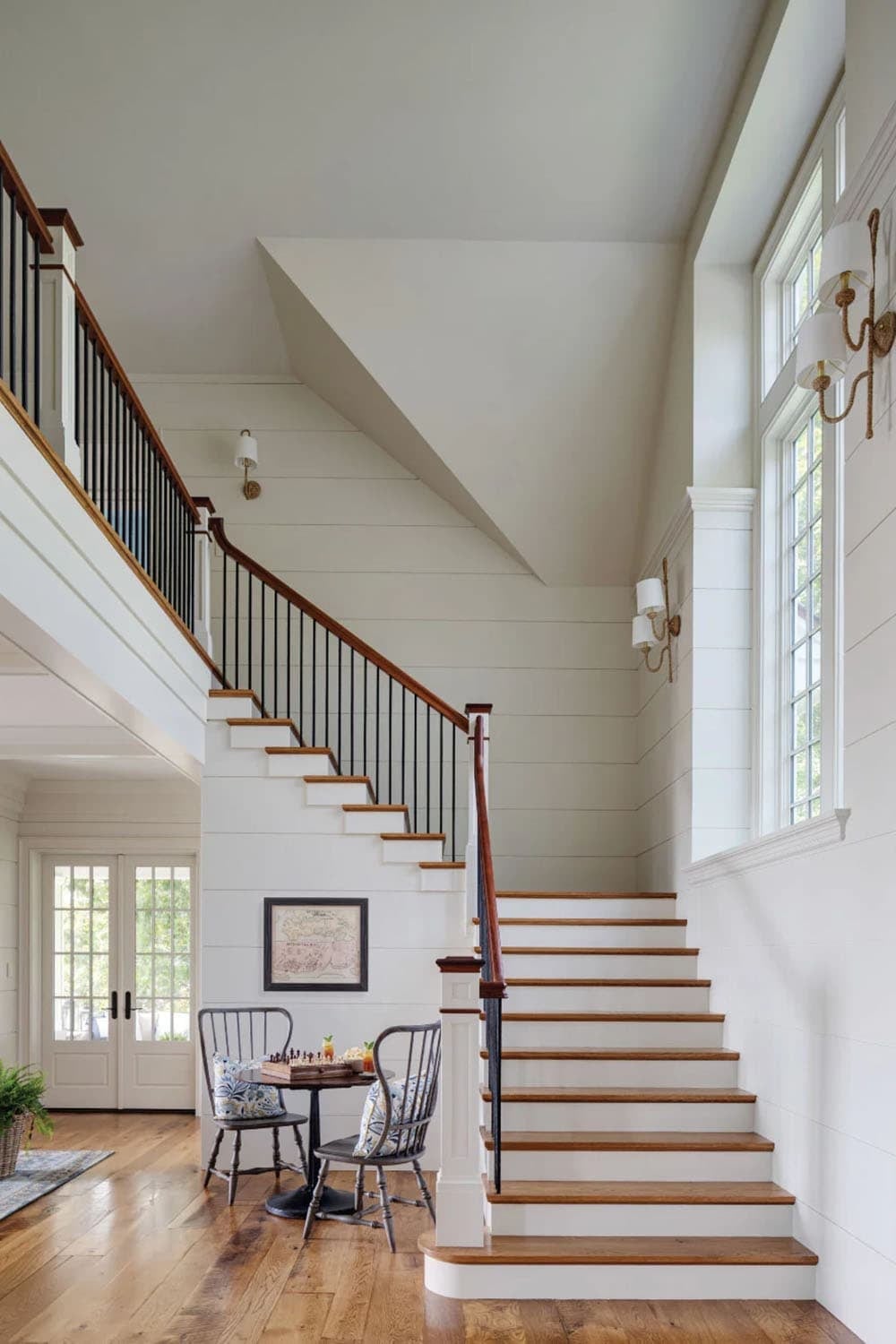 Staircase with white risers, oak treads, black balusters, and shiplap walls beneath a tall window