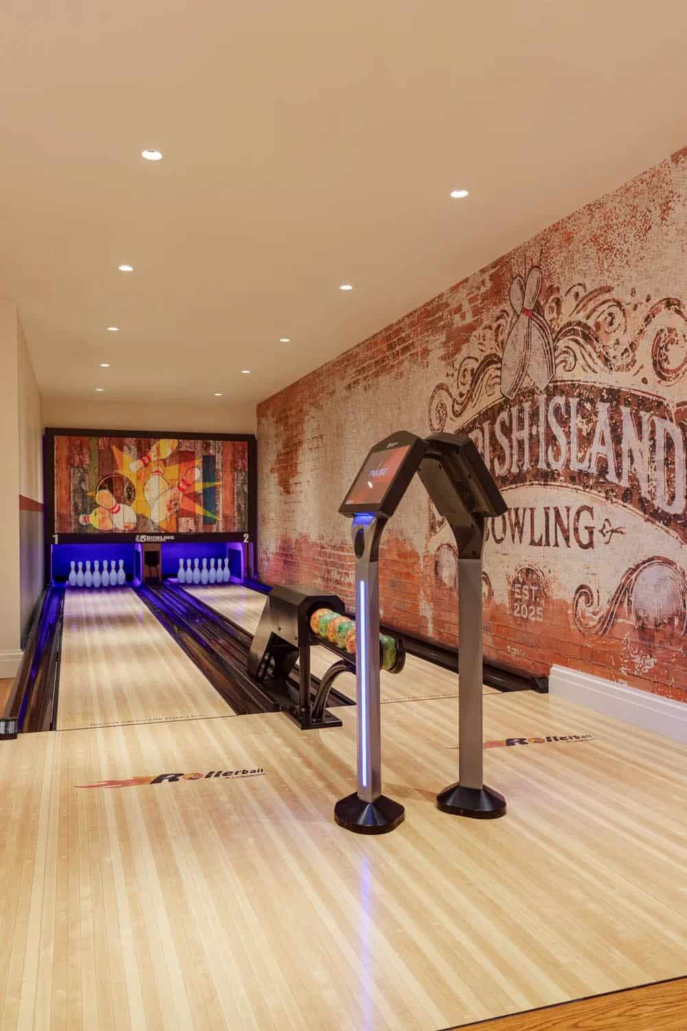 Two-lane home bowling alley with a digital scoring kiosk, and a colorful pin-deck backdrop