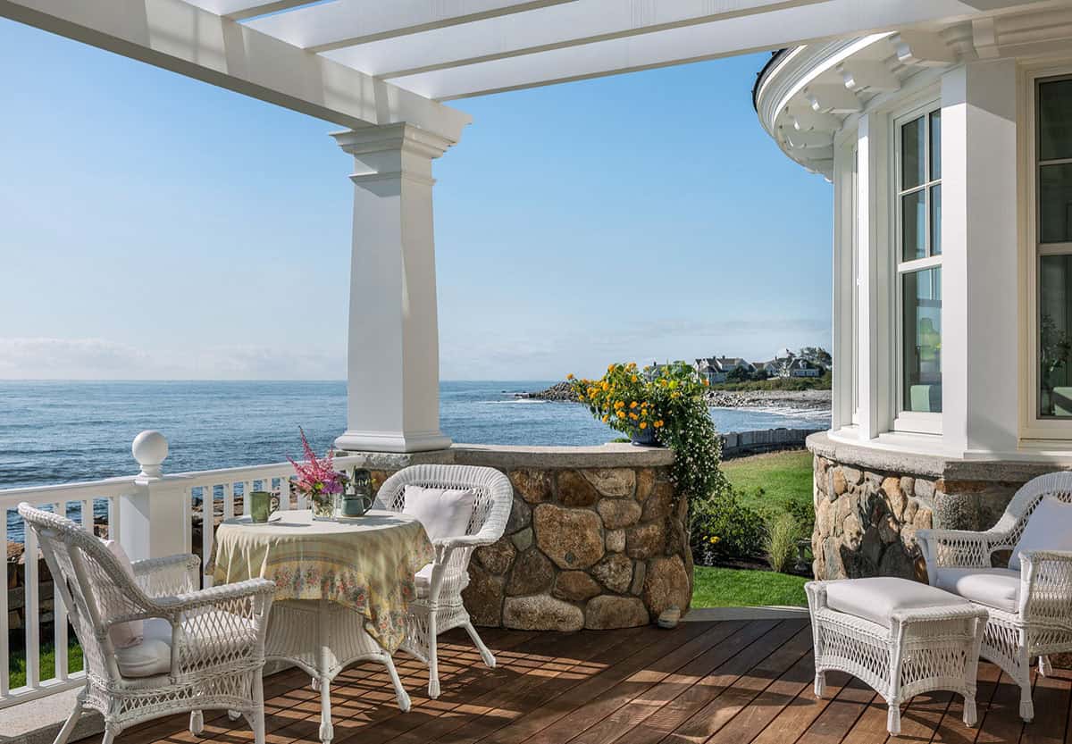 Porch with white wicker furniture and pergola overlooking the ocean