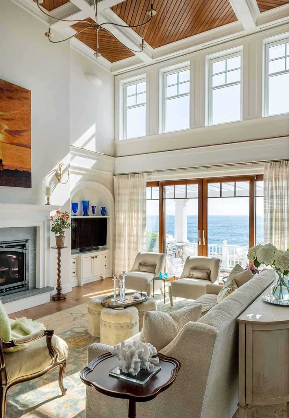 Two-story living room with coffered wood ceiling, fireplace, and sliding doors facing the sea