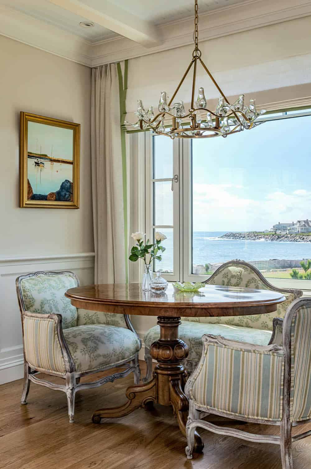 Breakfast nook with a round wood table, upholstered chairs, and a harbor view