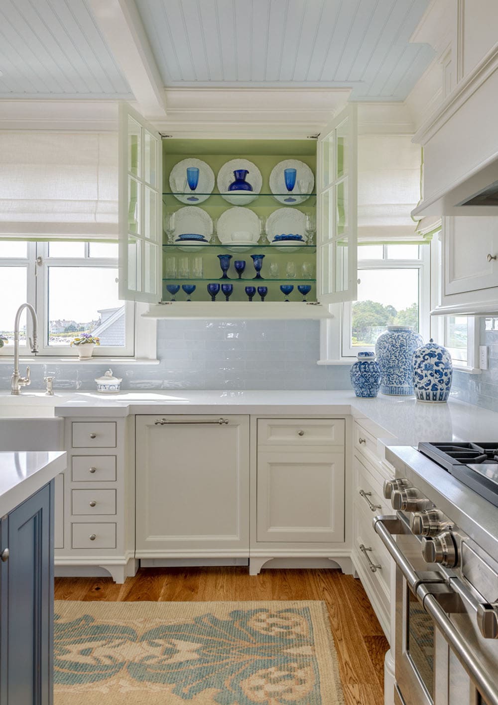 Kitchen corner with open glass cabinet showing blue-and-white dishes and a light blue backsplash