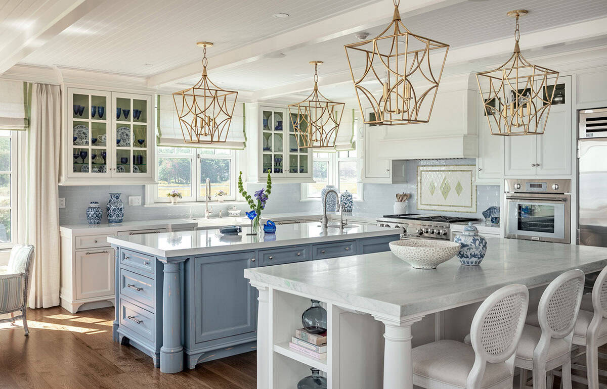 Kitchen with blue island, marble-topped seating island, and gold lantern pendants