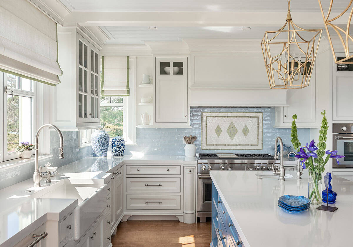 White kitchen with farmhouse sink, patterned tile backsplash, and gold pendant lights