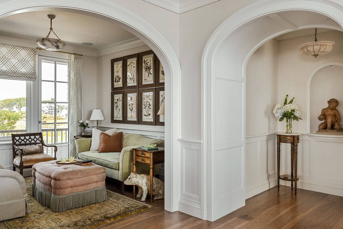 Two arched doorways leading to a sitting nook with framed botanicals and a statue niche