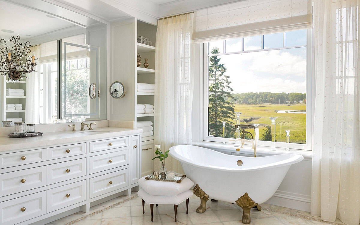 Primary bath with clawfoot tub, marsh view, and white vanity with brass knobs