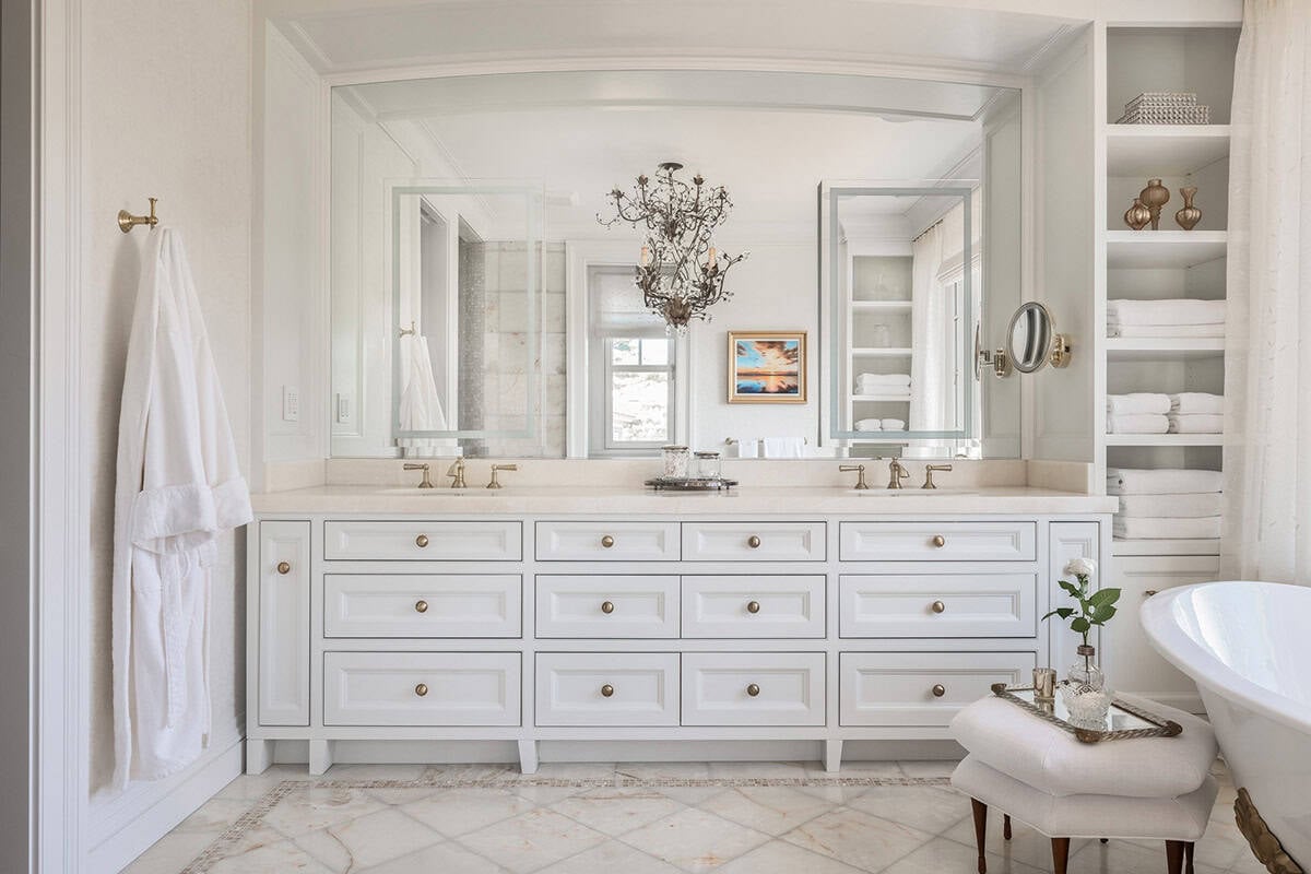 Double vanity with large mirror, brass fixtures, and built-in towel shelves