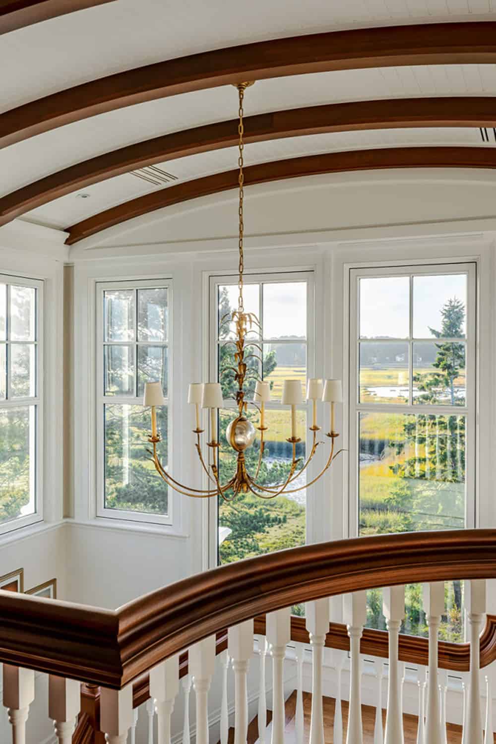 Close view of the curved beams, gold chandelier, and marsh views through tall windows