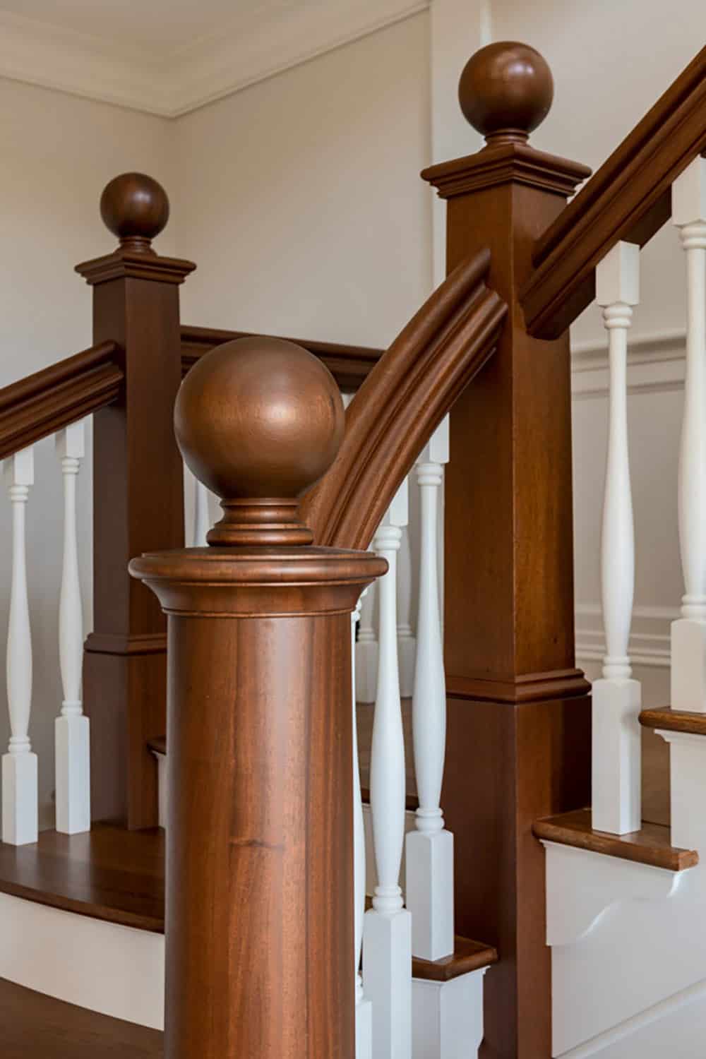 Close view of wood newel posts with ball finials and white turned balusters