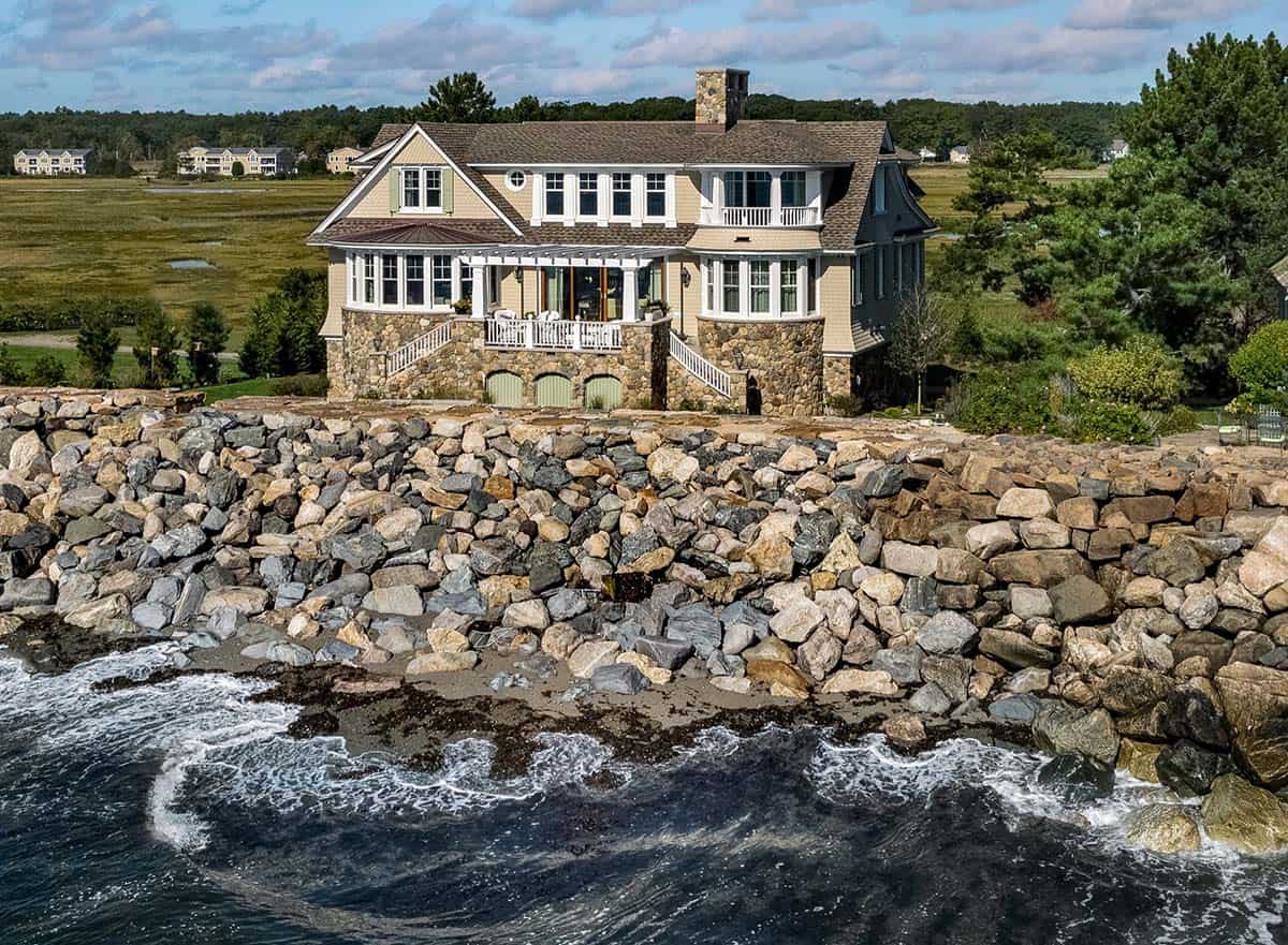 Aerial view of the home with marsh behind and rocky coast in front