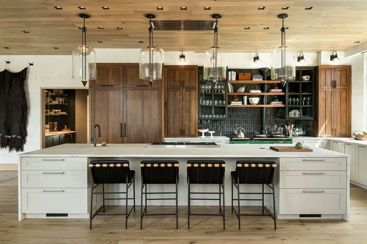 Long marble kitchen island with leather counter stools and glass pendants