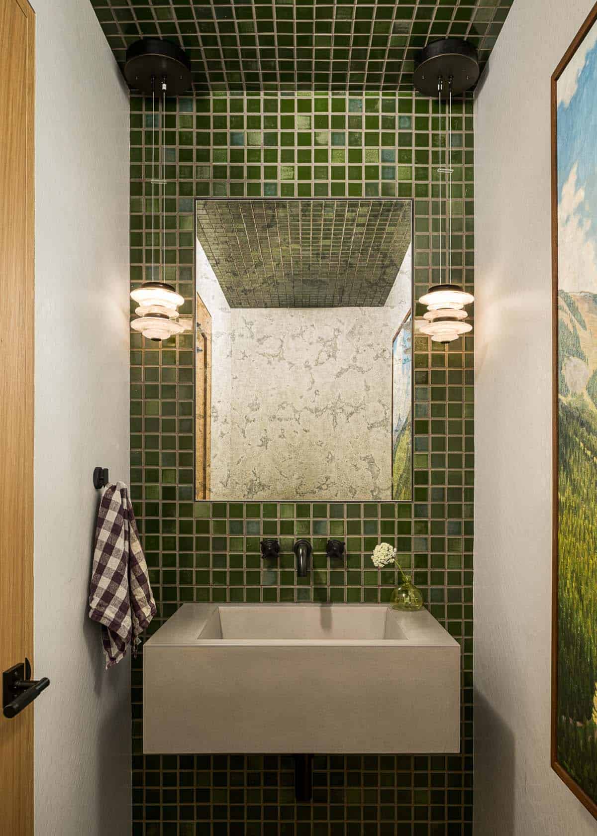Powder room with green tile, floating concrete sink, and pendant lights