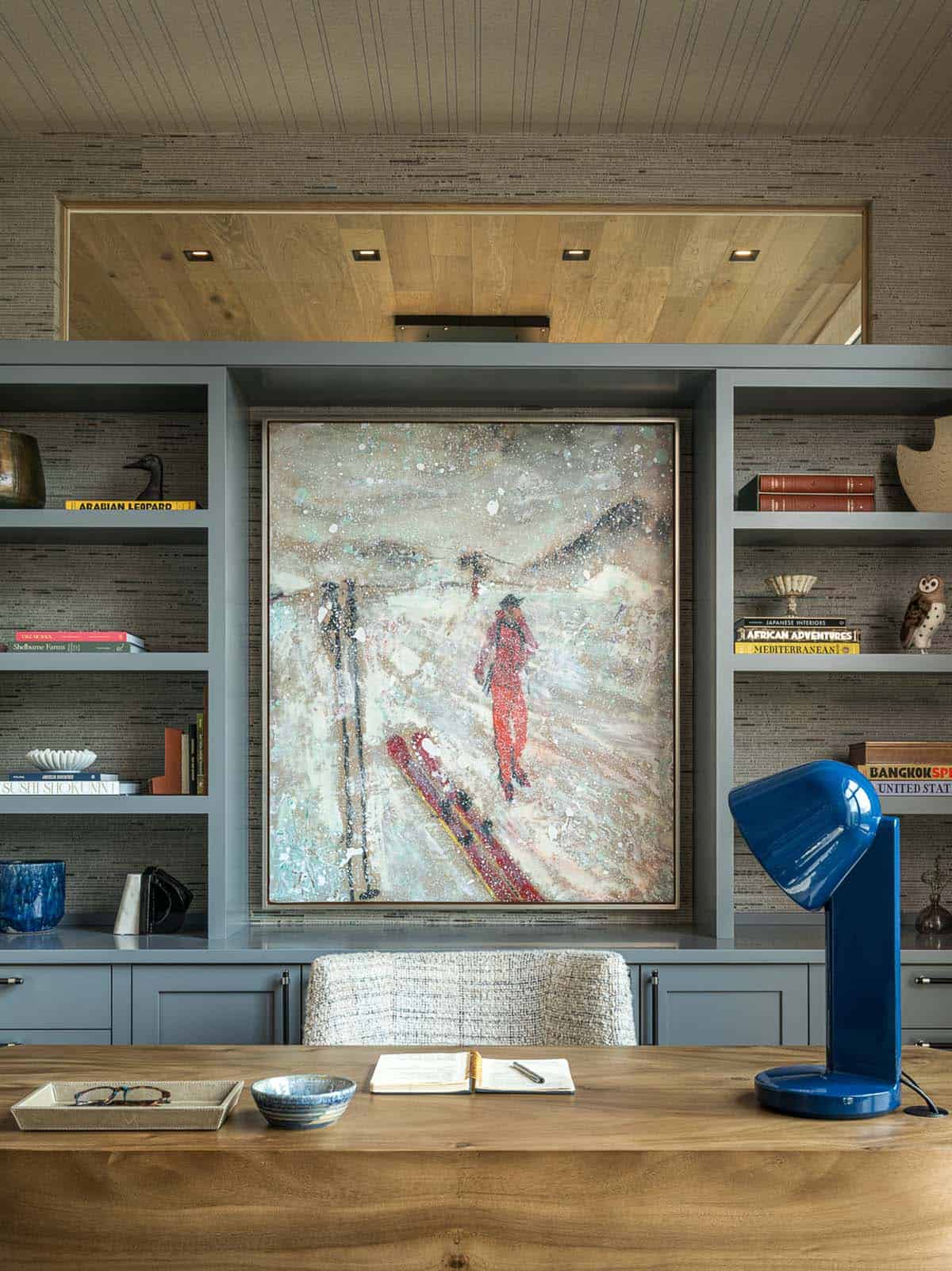Home office desk facing gray built-ins and ski painting