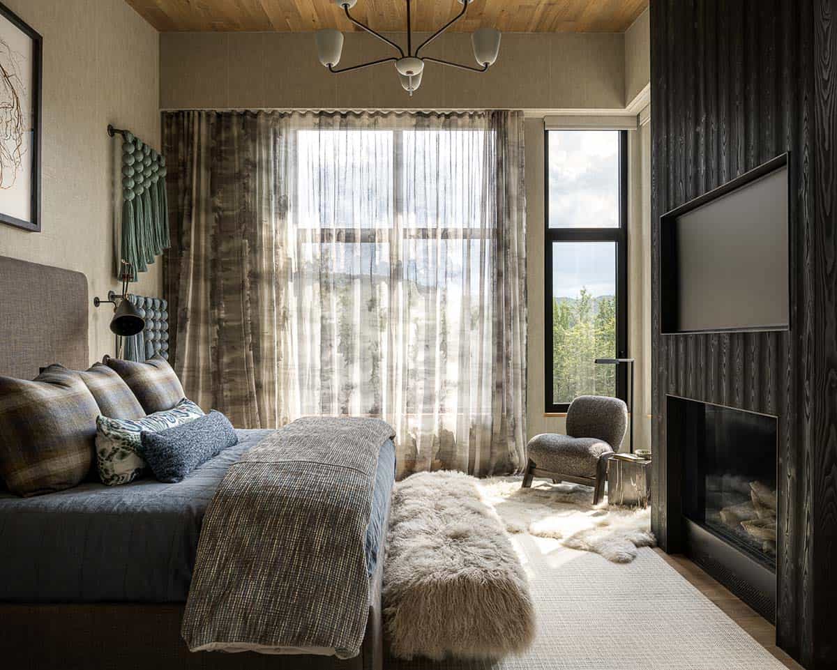 Primary bedroom with sheer curtains, charred wood fireplace wall, and sheepskin