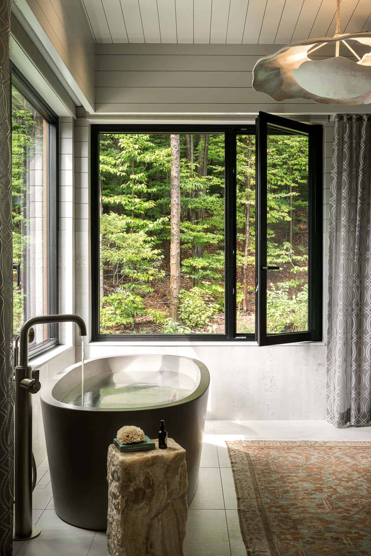 Freestanding concrete tub facing wooded hillside in primary bathroom