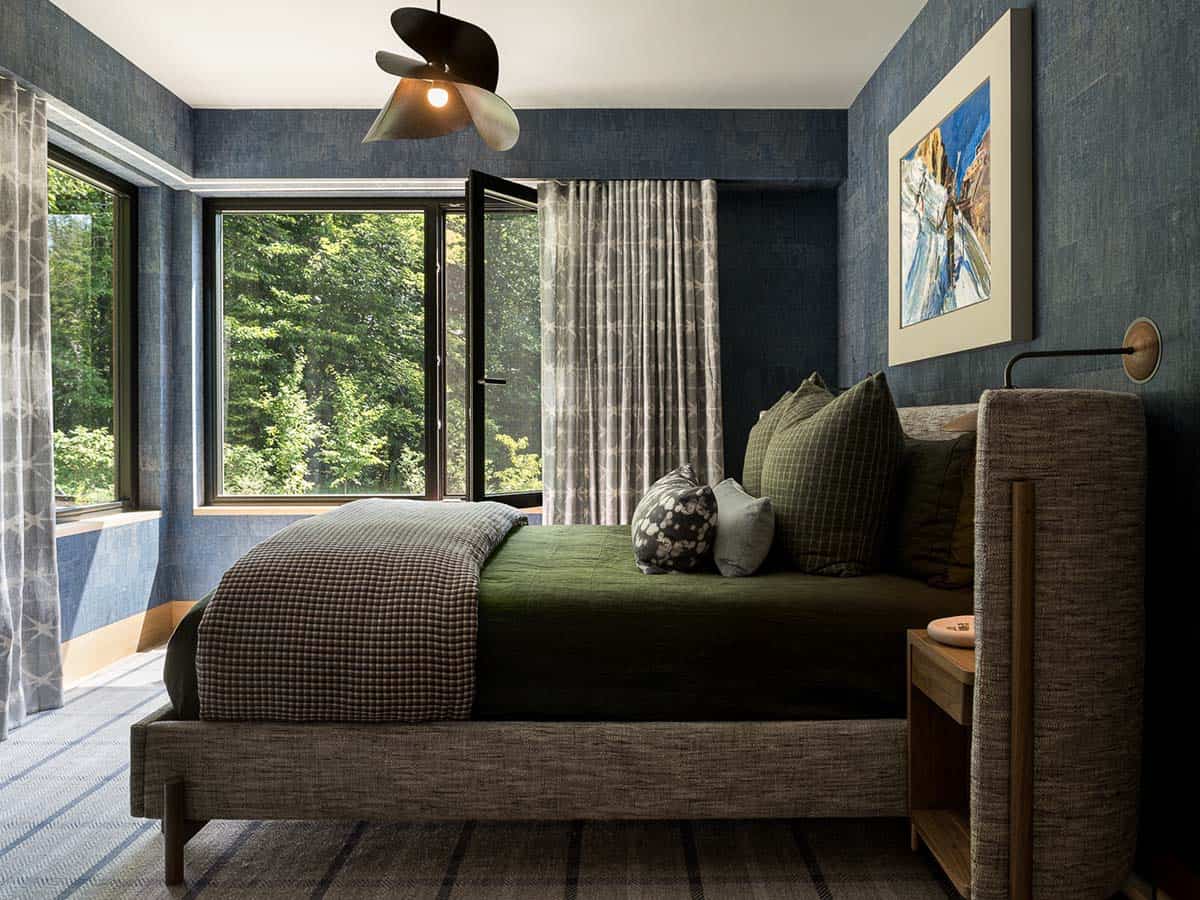 Bedroom with blue grasscloth walls and corner windows facing the yard