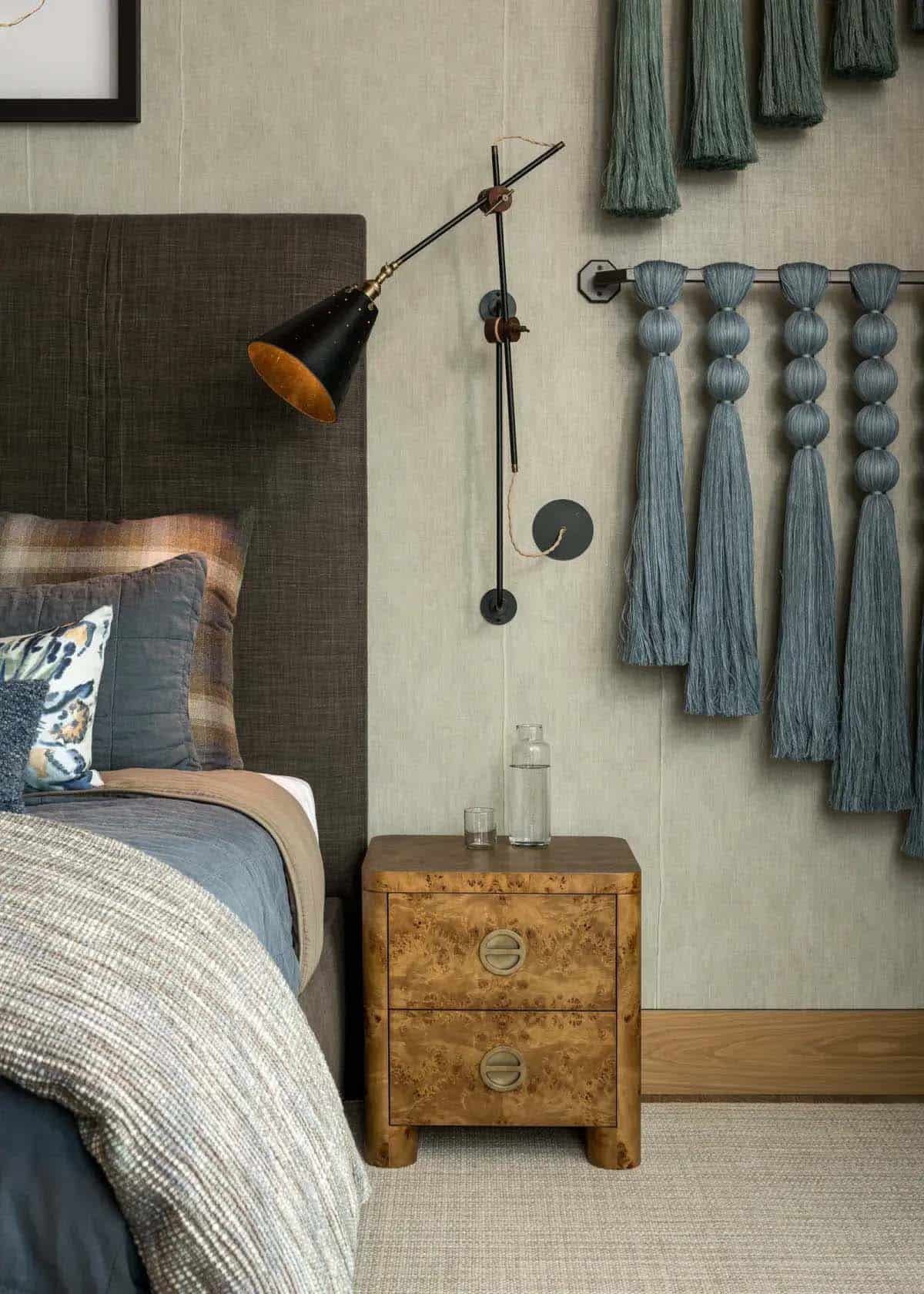 Burl wood nightstand with swing-arm sconce and blue tassel wall art