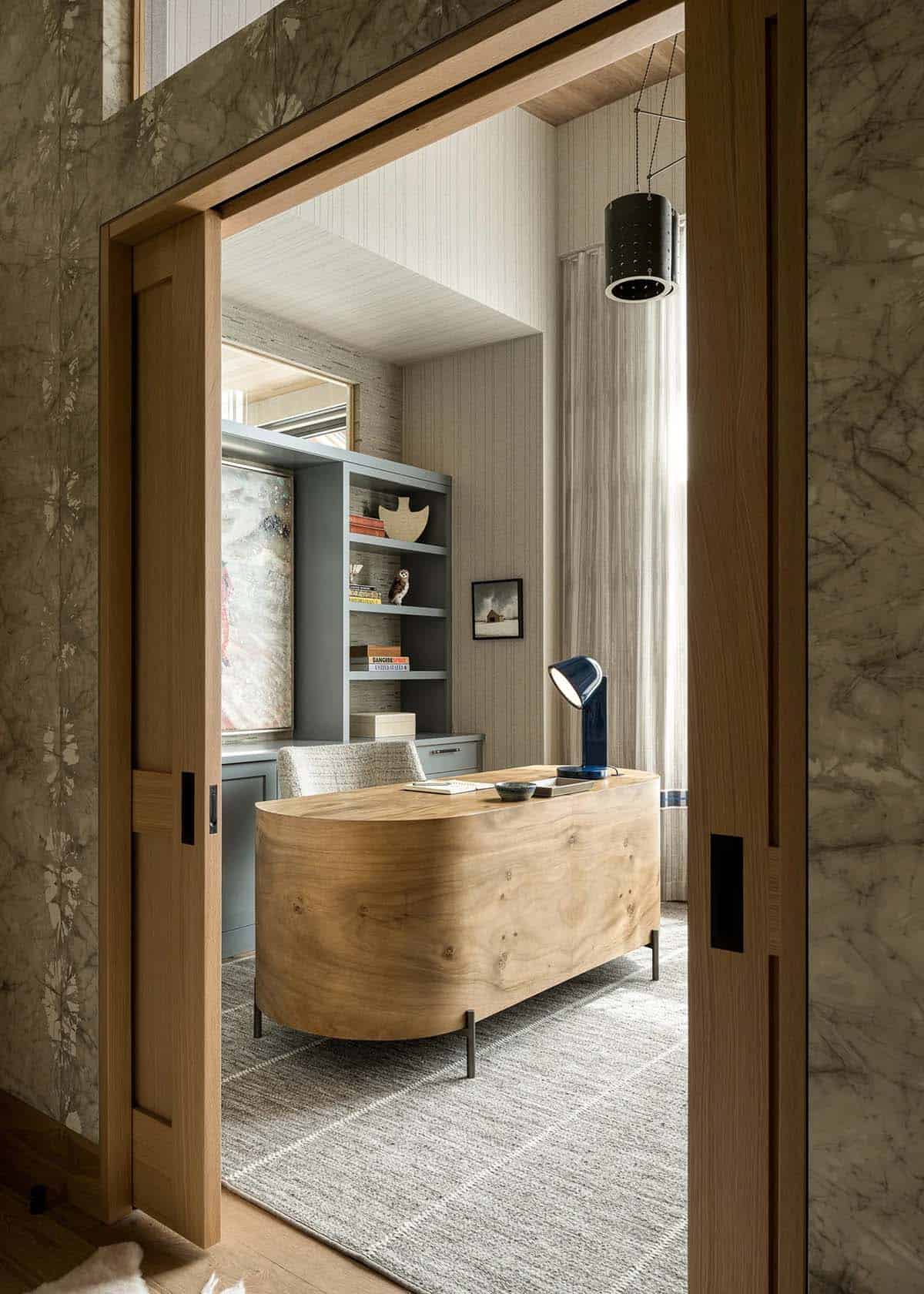 Home office with curved wood desk seen through oak pocket doors