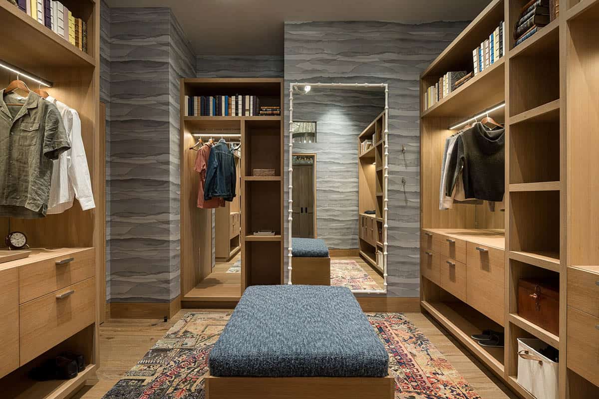 Walk-in closet with oak shelving, blue bench, and vintage rug